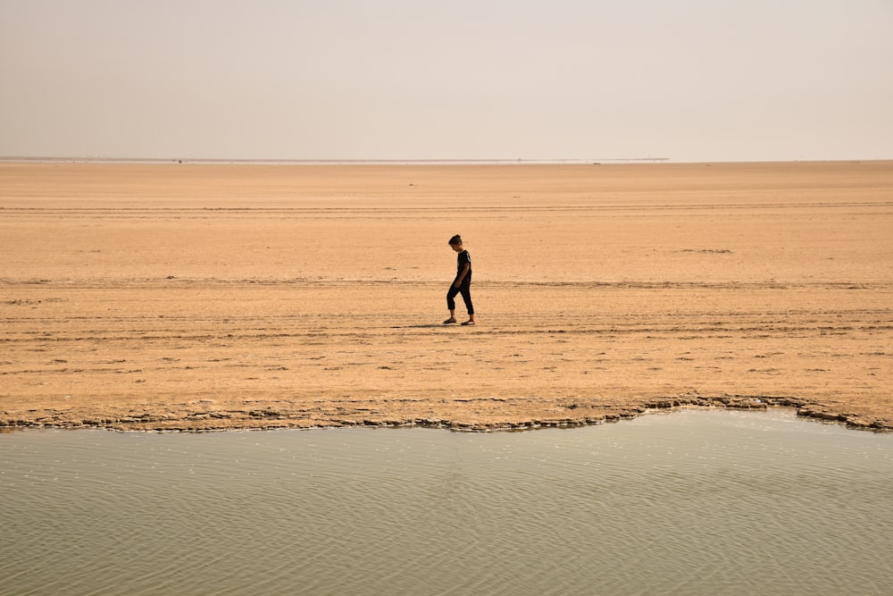 Homme marchant sur le sable brun pendant la journée