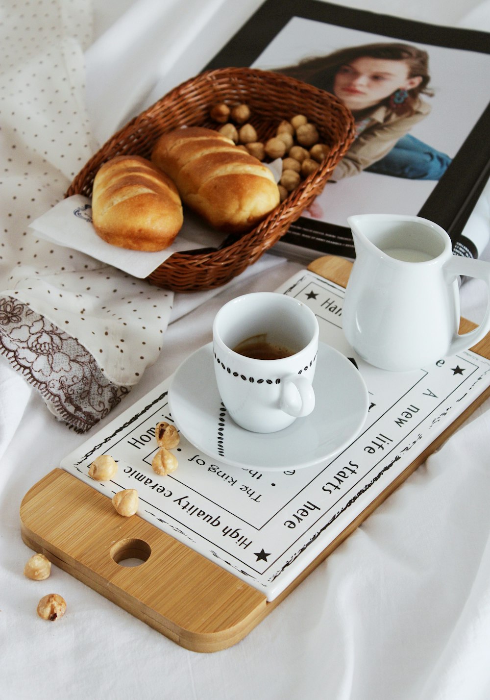 Tasse en céramique blanche sur assiette en céramique blanche à côté du pain brun sur plateau en bois brun
