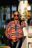 A confident plus-size model walking down a city street in a bold, colorful jacket.