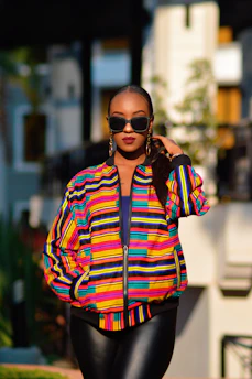 A confident plus-size model walking down a city street in a bold, colorful jacket.