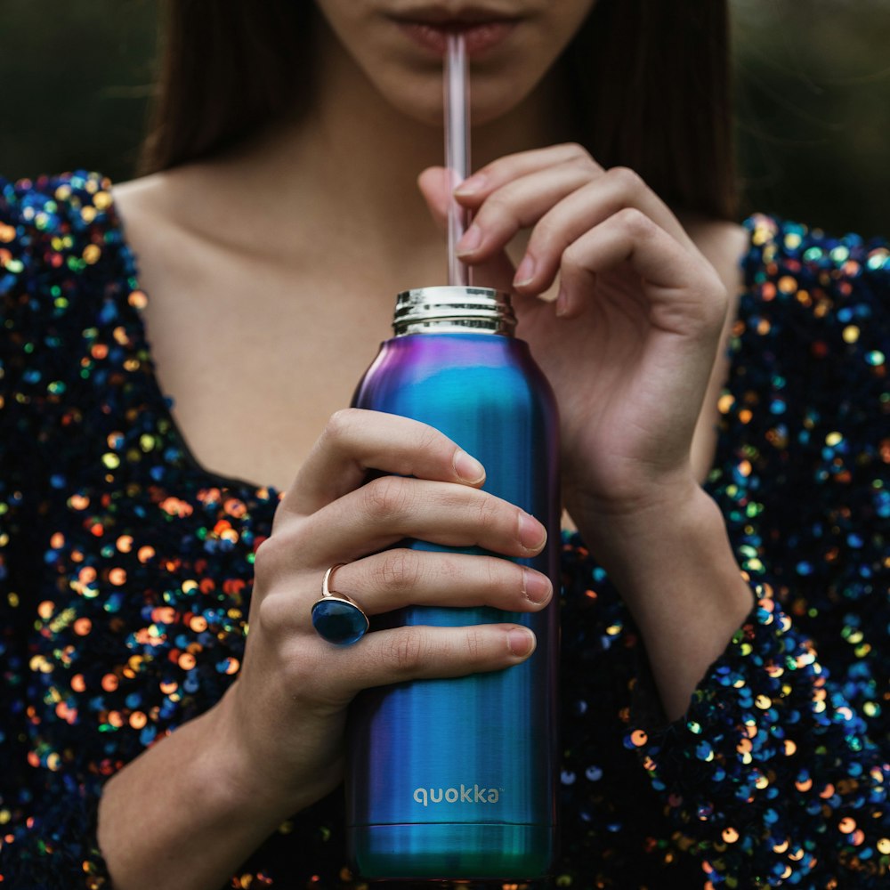 woman in black and white floral dress holding blue bottle