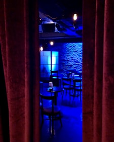A cozy comedy club setting with bright lights and a small stage.