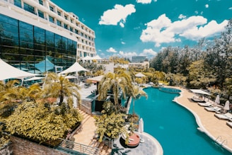 white and blue concrete building near green trees and body of water during daytime