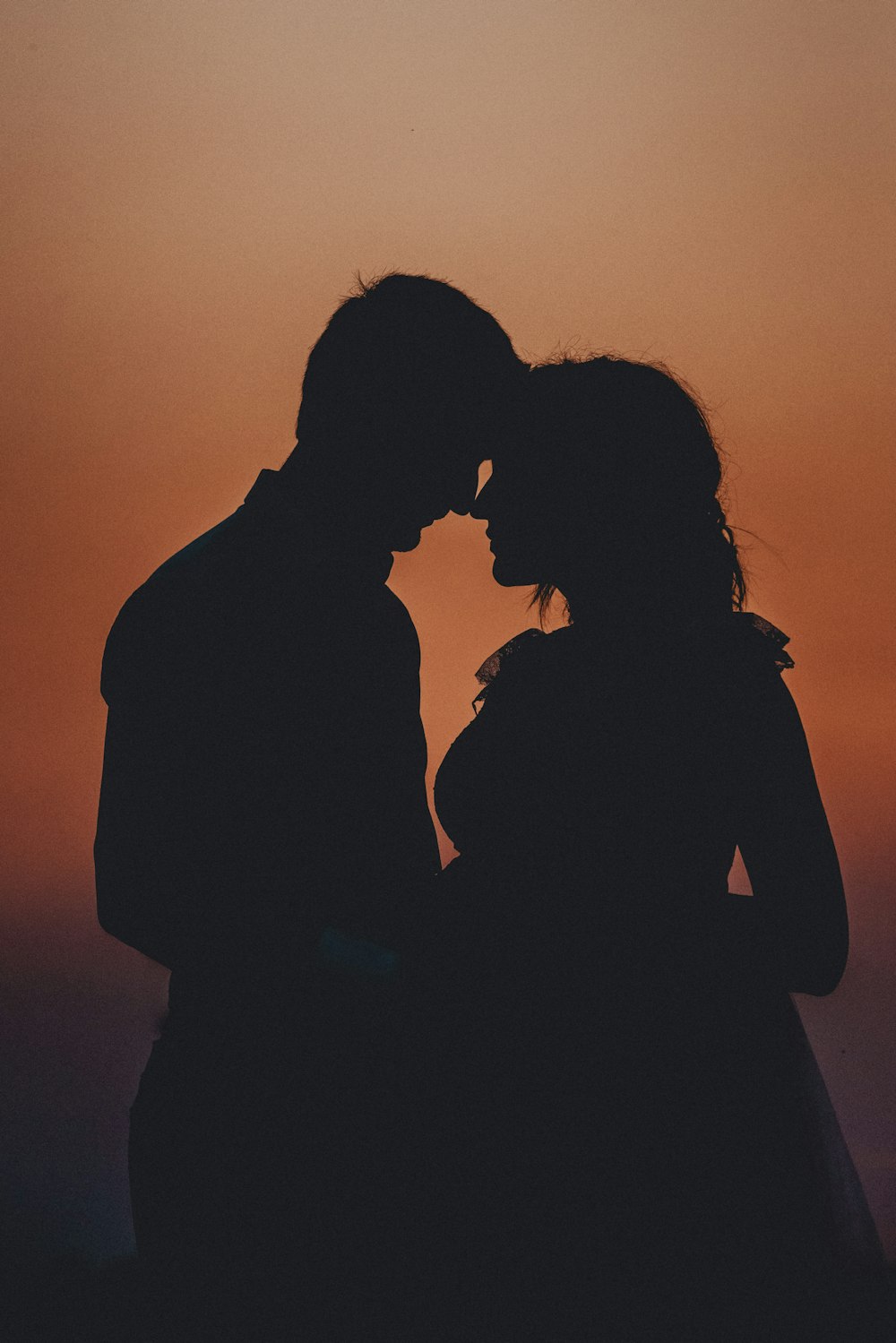 silhouette of woman and man kissing during sunset
