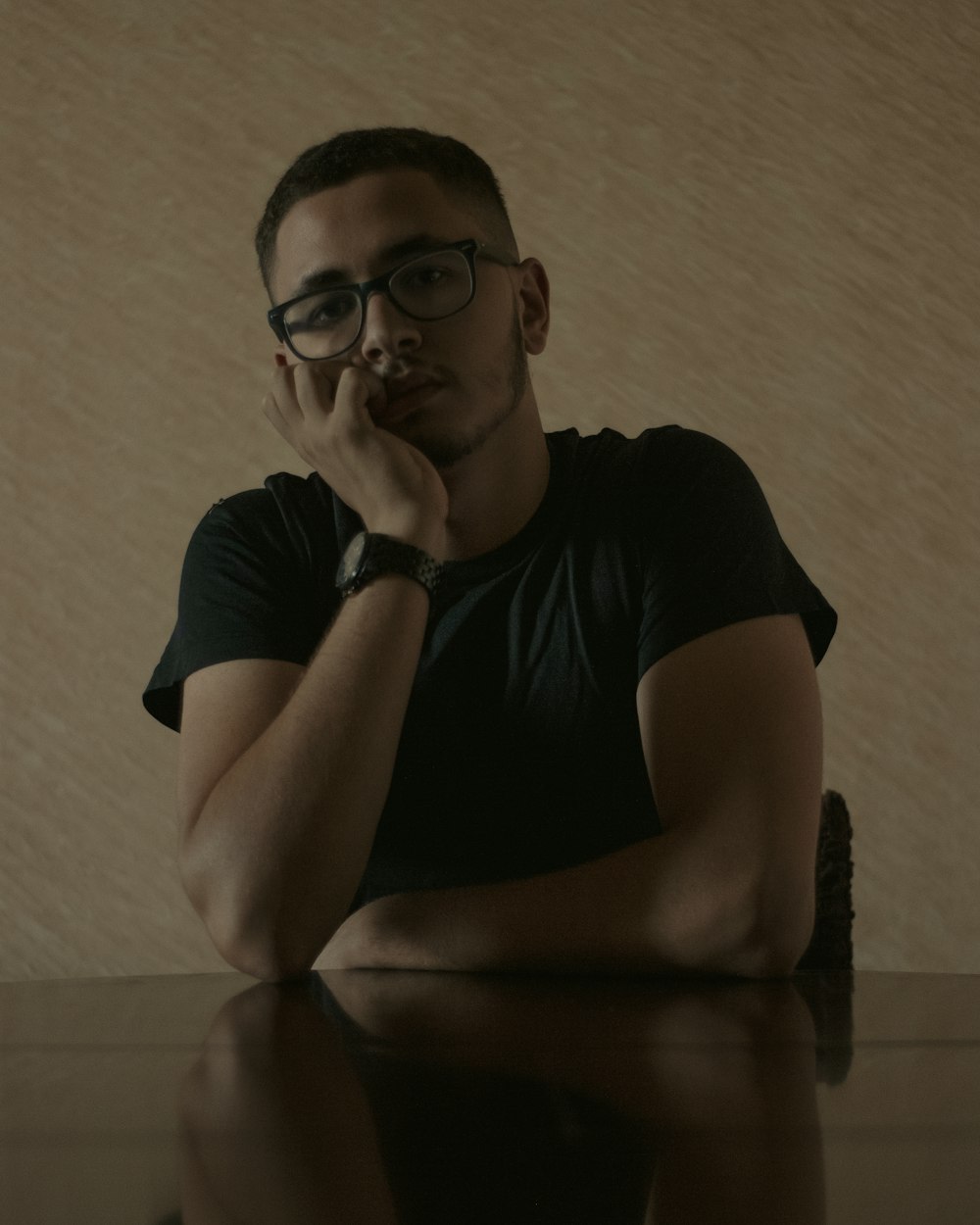 a man sitting at a table with his hand on his chin