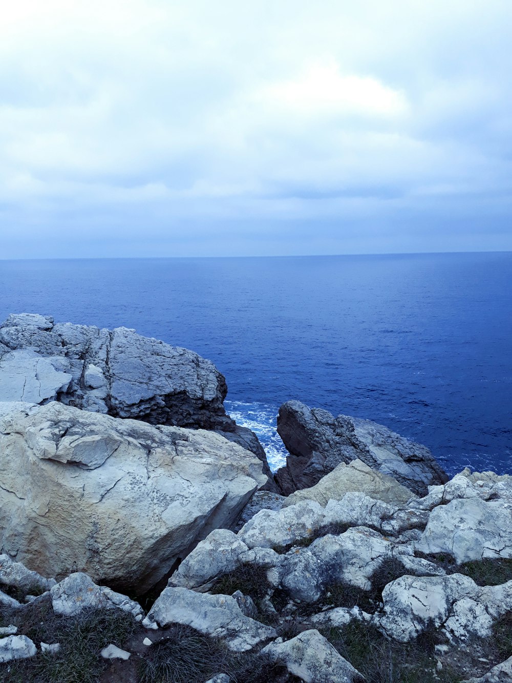 Una persona seduta sulla cima di una grande roccia vicino all'oceano