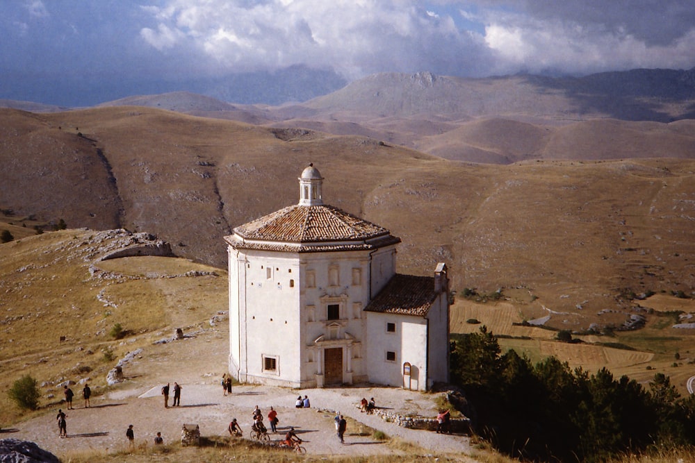 a white building with a brown roof on top of a hill