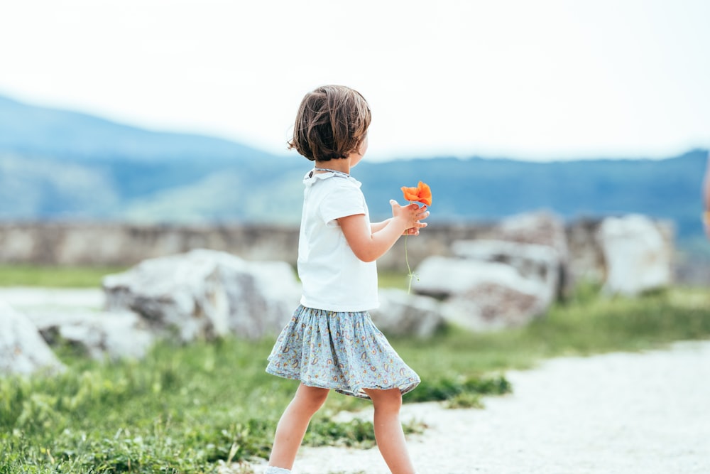 une petite fille qui tient une fleur