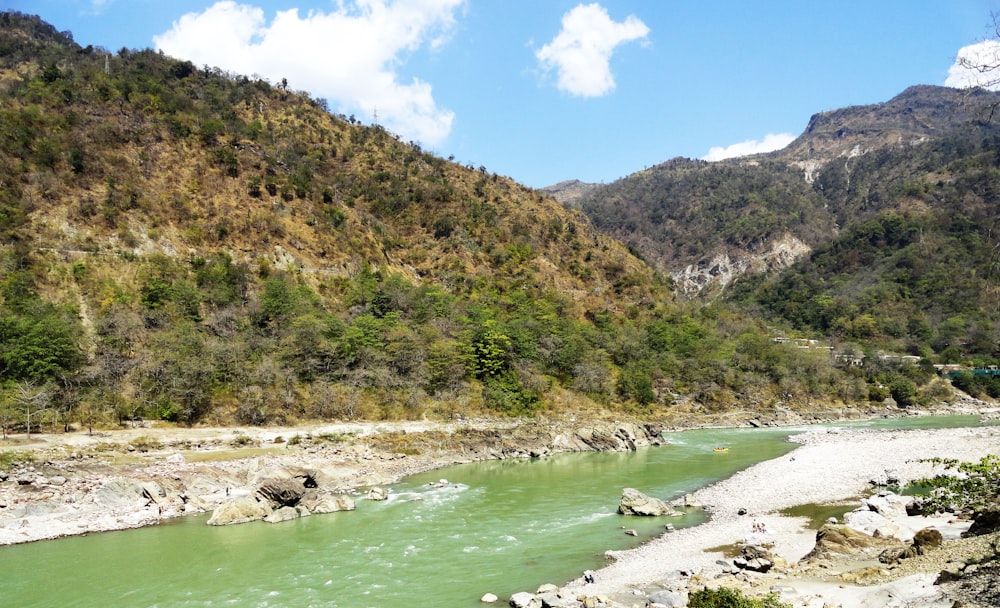 Montagne verdi e marroni accanto al fiume sotto il cielo blu durante il giorno