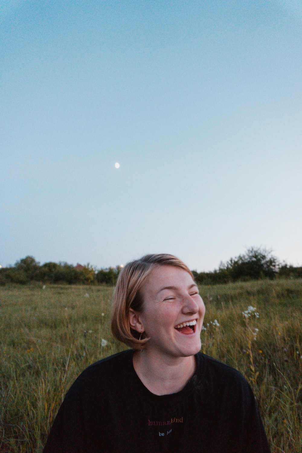 a woman laughing in a field of tall grass