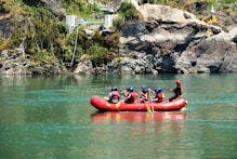 people riding red kayak on river during daytime