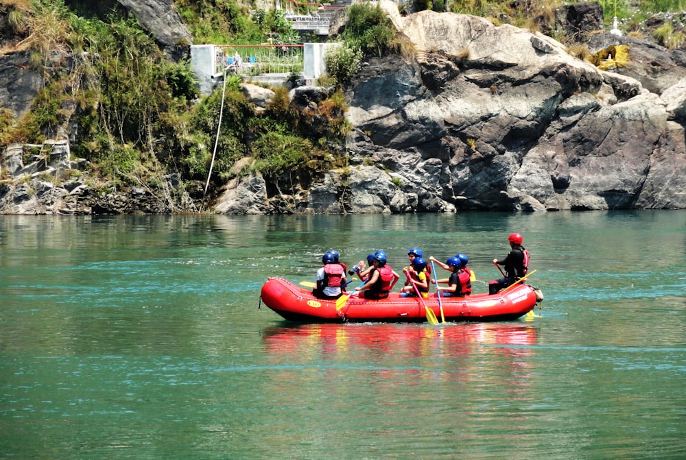 people riding red kayak on river during daytime