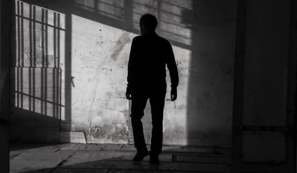 a man standing in a dark room next to a jail cell