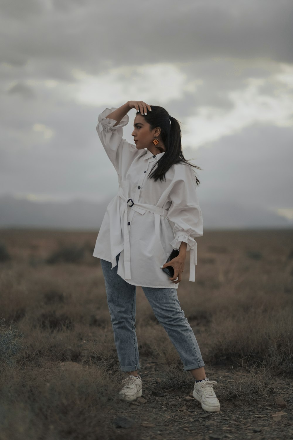 a woman in a white shirt and jeans standing in a field