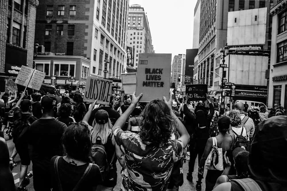 a group of people walking down a street holding signs