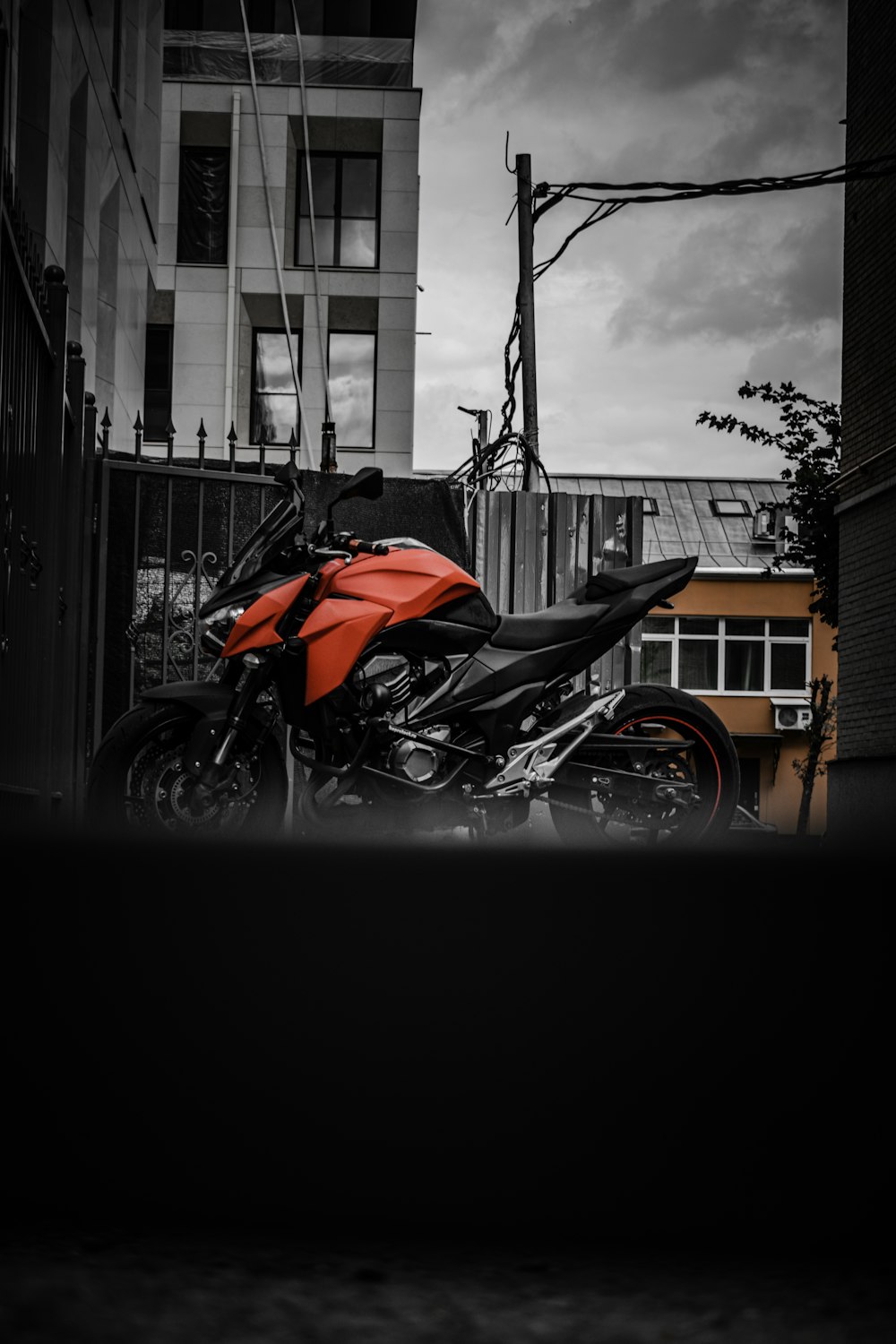 black and orange naked motorcycle parked beside building