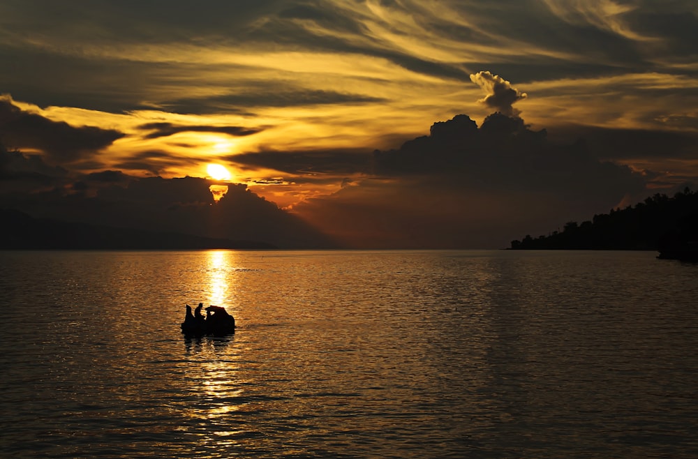 Silhouette von Menschen auf dem Boot während des Sonnenuntergangs