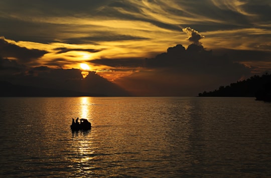 silhouette of people on boat during sunset in Lake Toba Indonesia