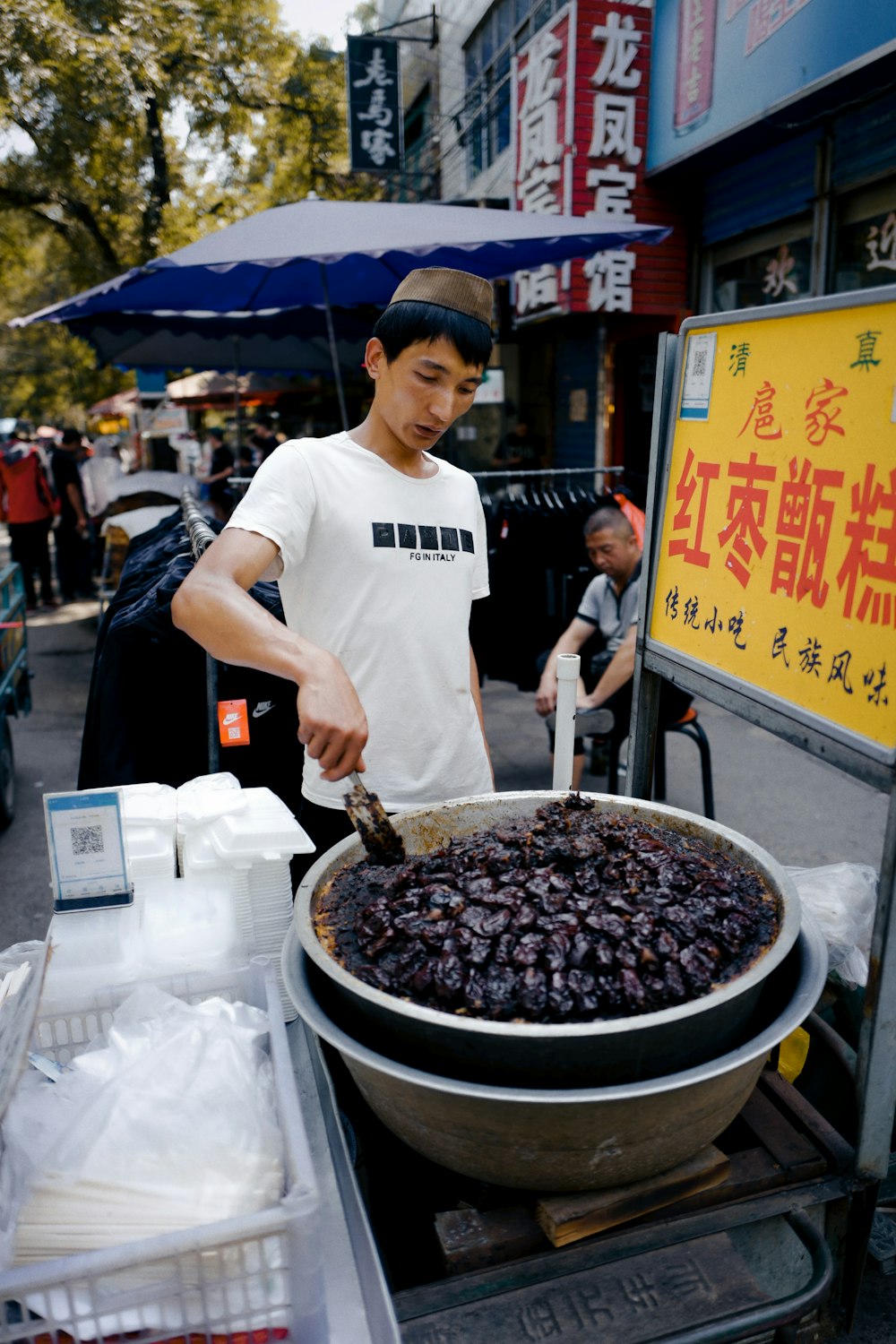 man in white crew neck t-shirt holding black plastic bowl with food during daytime