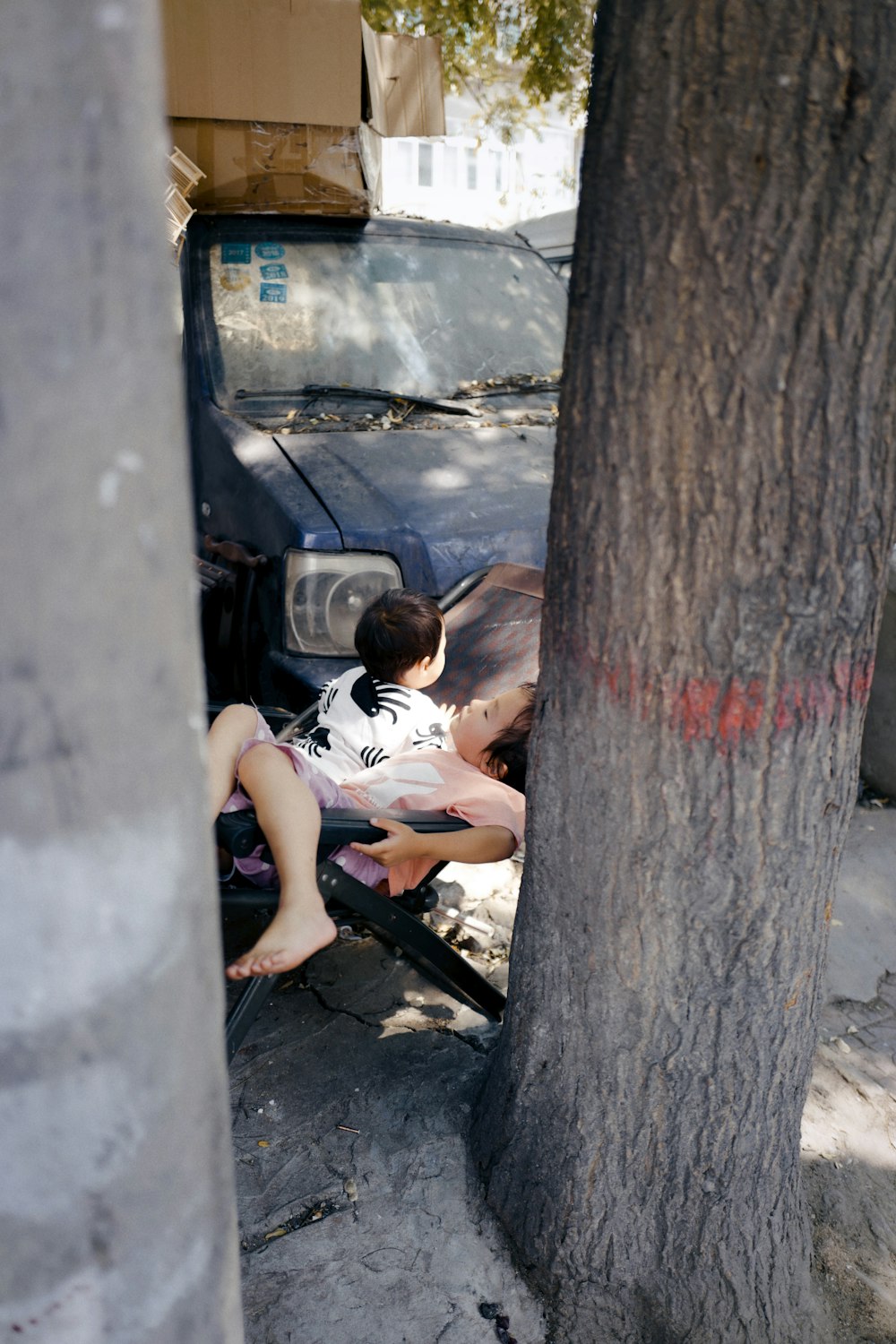 a young boy sitting on the hood of a car