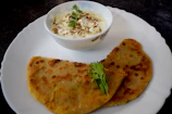Freshly baked parathas stacked neatly with a bowl of homemade yogurt.