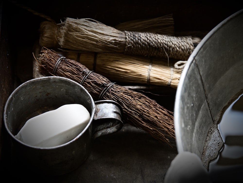 silver steel bucket beside brown broom