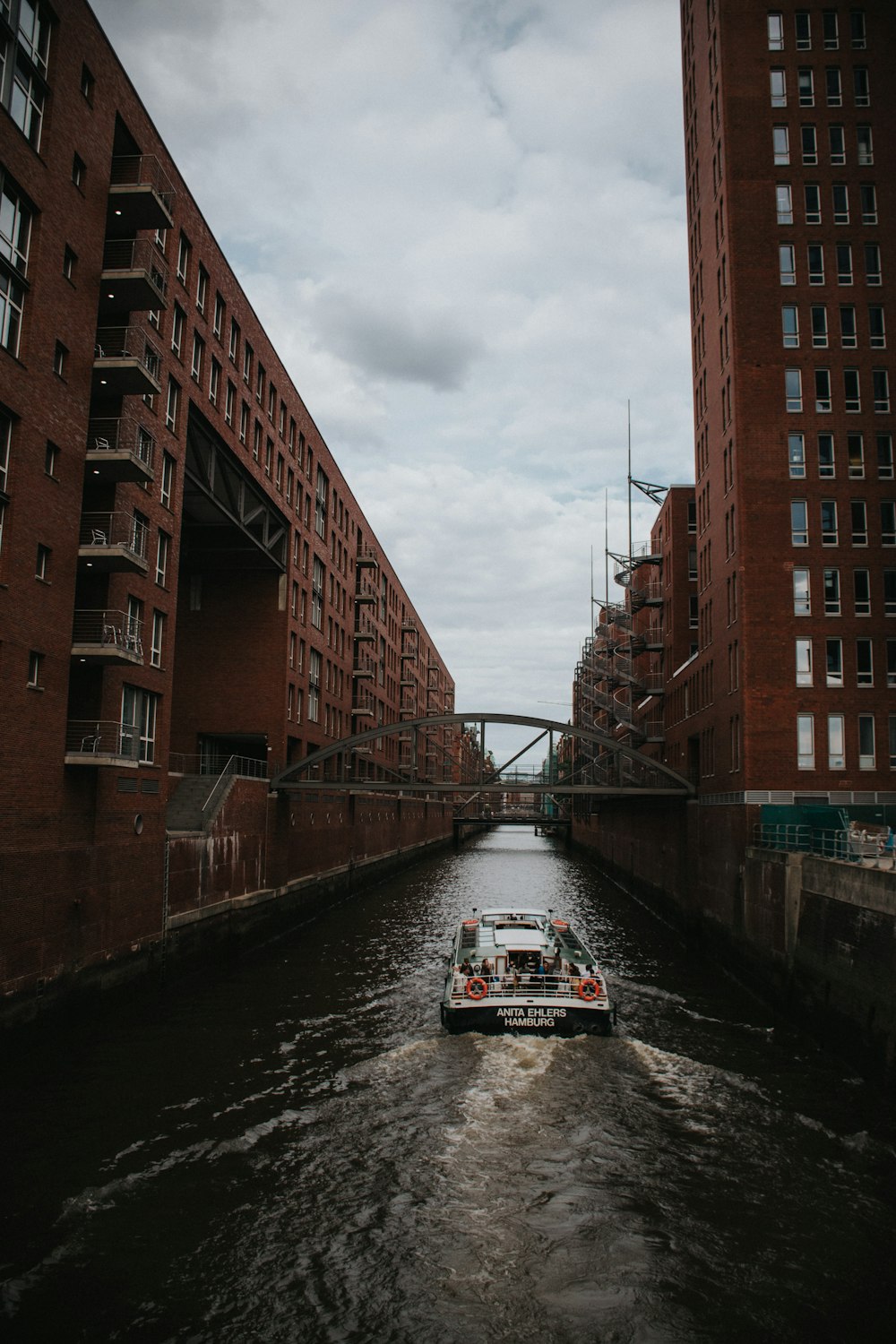 white and black boat on river between brown concrete building during daytime