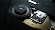 A close-up view of the internal mechanism of a DVD or CD drive, showcasing the laser lens and the spindle motor in detail. The metal components and black plastic parts are visible, with the intricate design and screws highlighted.