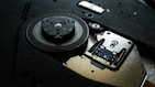 A close-up view of the internal mechanism of a DVD or CD drive, showcasing the laser lens and the spindle motor in detail. The metal components and black plastic parts are visible, with the intricate design and screws highlighted.