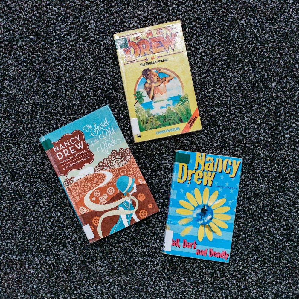 Tres libros encima de una alfombra