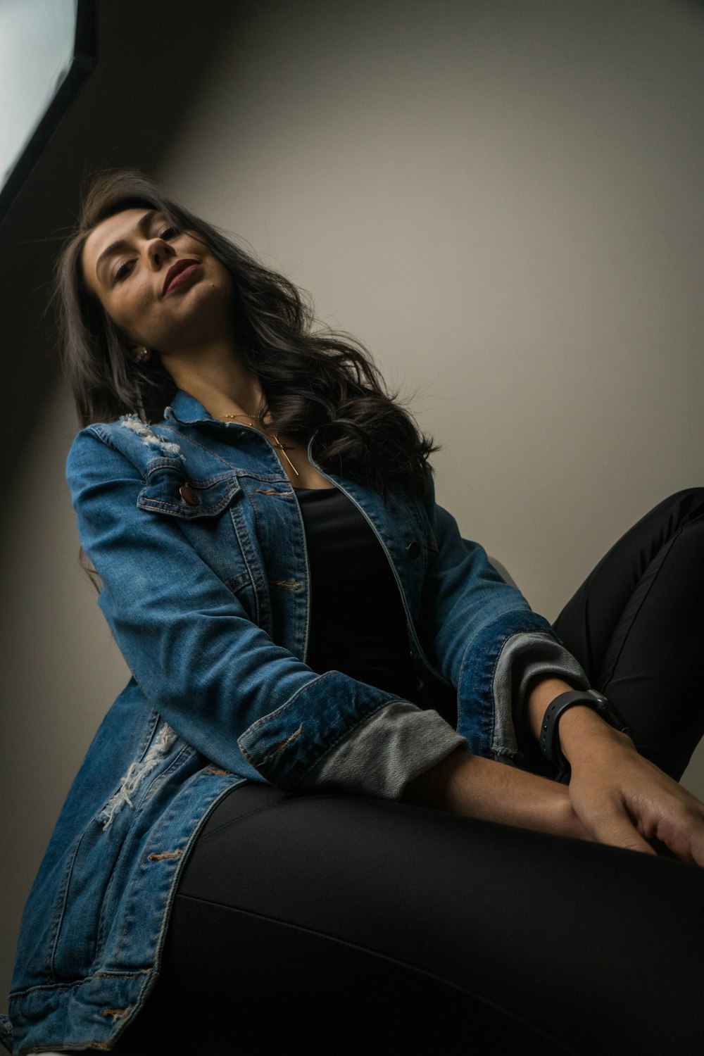 woman in blue denim jacket and black pants sitting on black couch