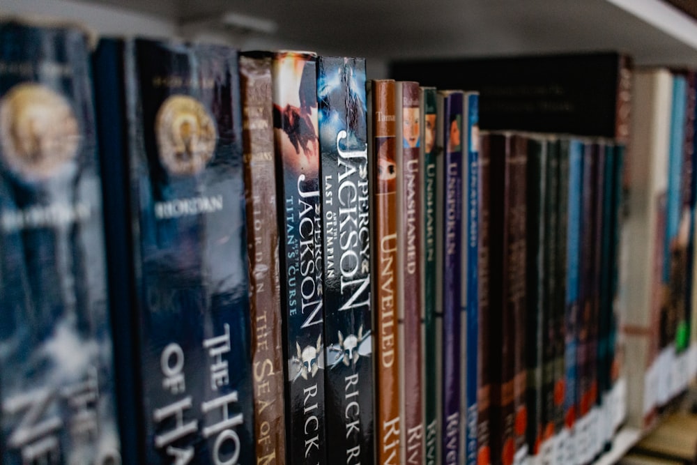 a row of books sitting on top of a wooden shelf