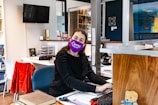 a woman sitting at a desk with a purple mask on her face
