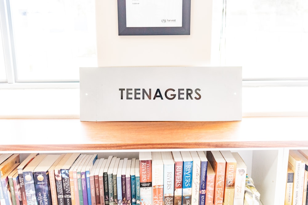 uma estante de livros com uma placa que diz adolescentes nela