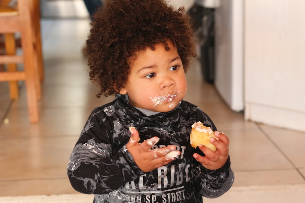 girl in black and white long sleeve shirt eating yellow fruit