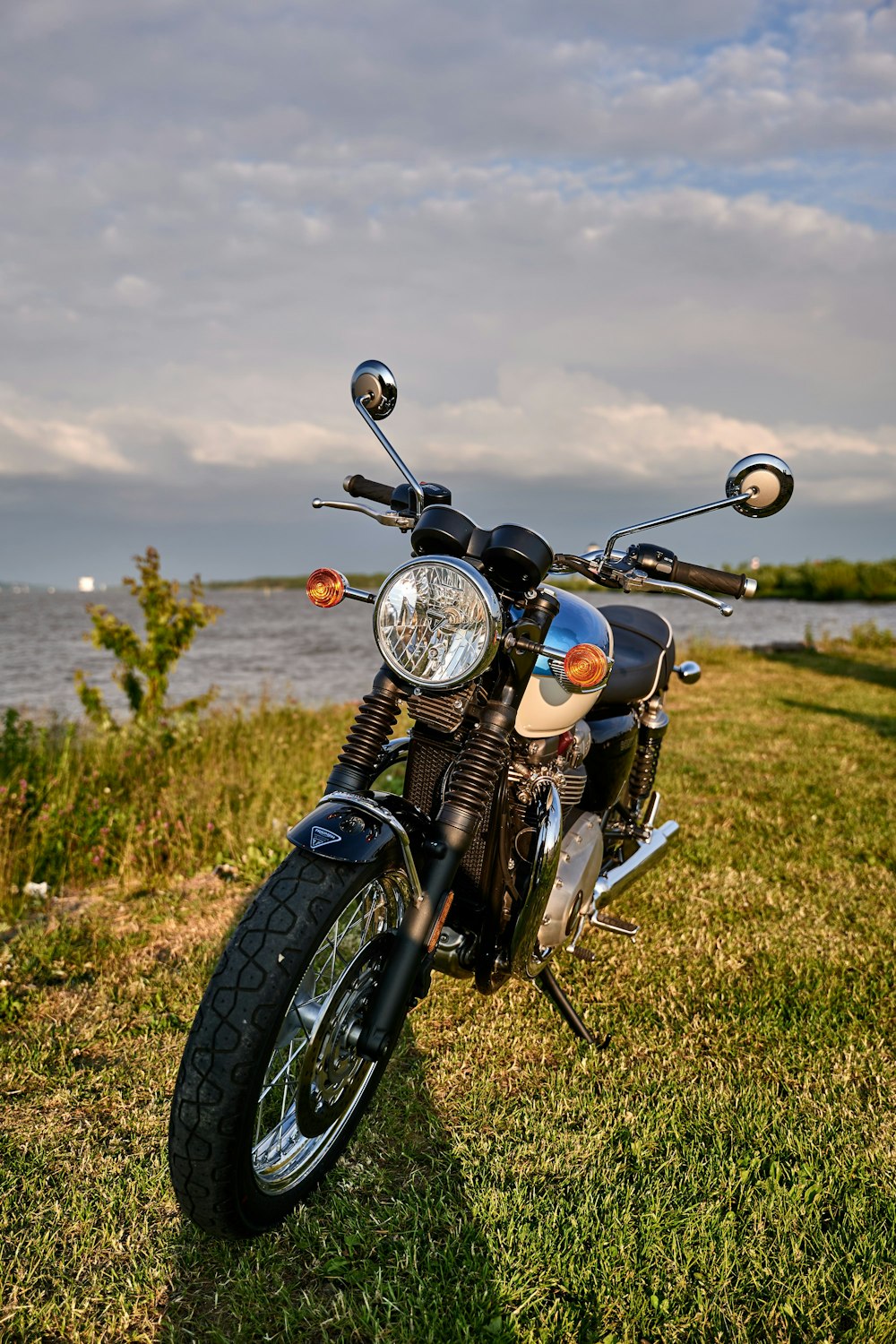 a motorcycle parked in the grass near a body of water