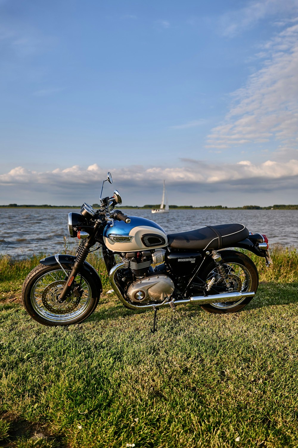 a motorcycle is parked on the grass near the water