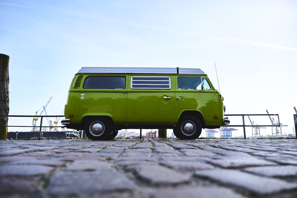 a green van is parked on a cobblestone road