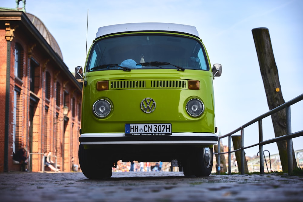 a green van parked in front of a brick building