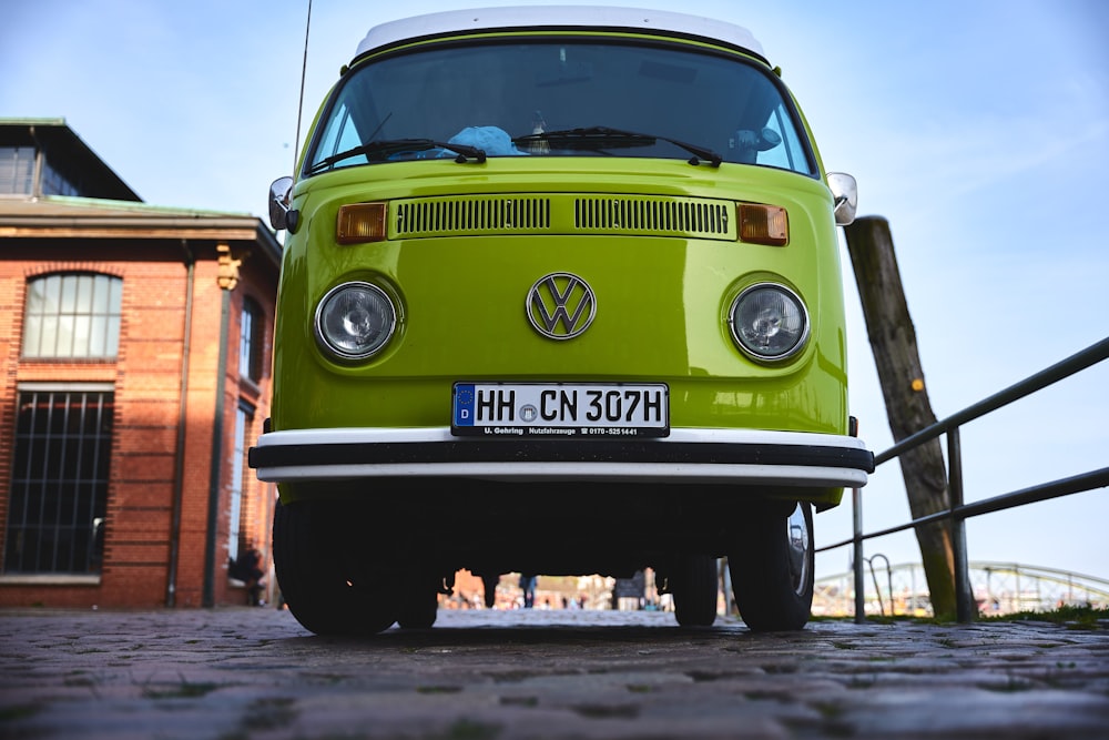 a green vw bus parked in front of a brick building