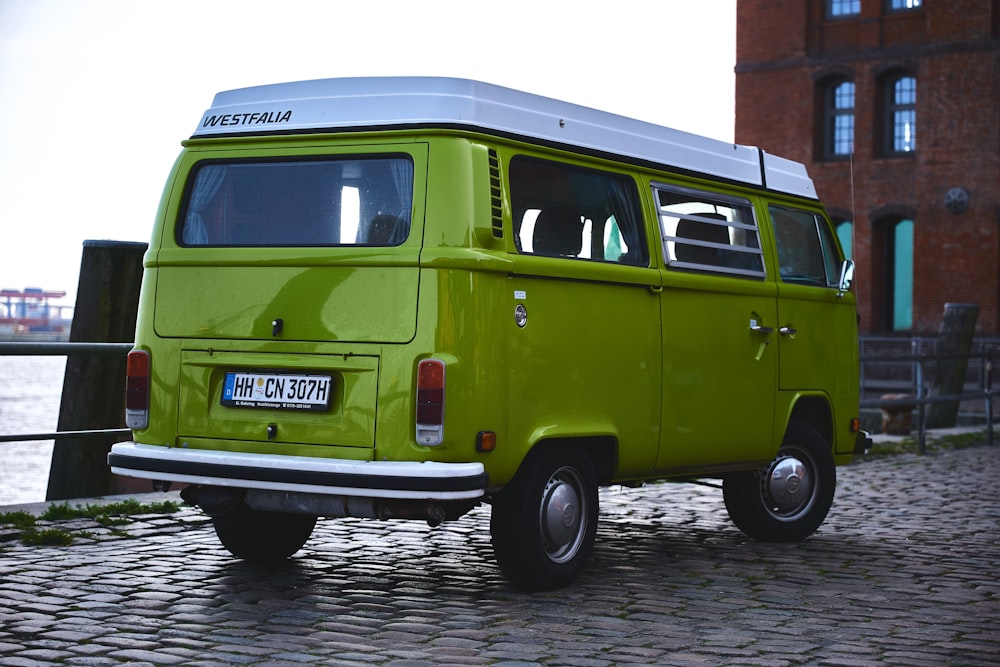 green and white volkswagen t-2 van parked on gray concrete pavement during daytime