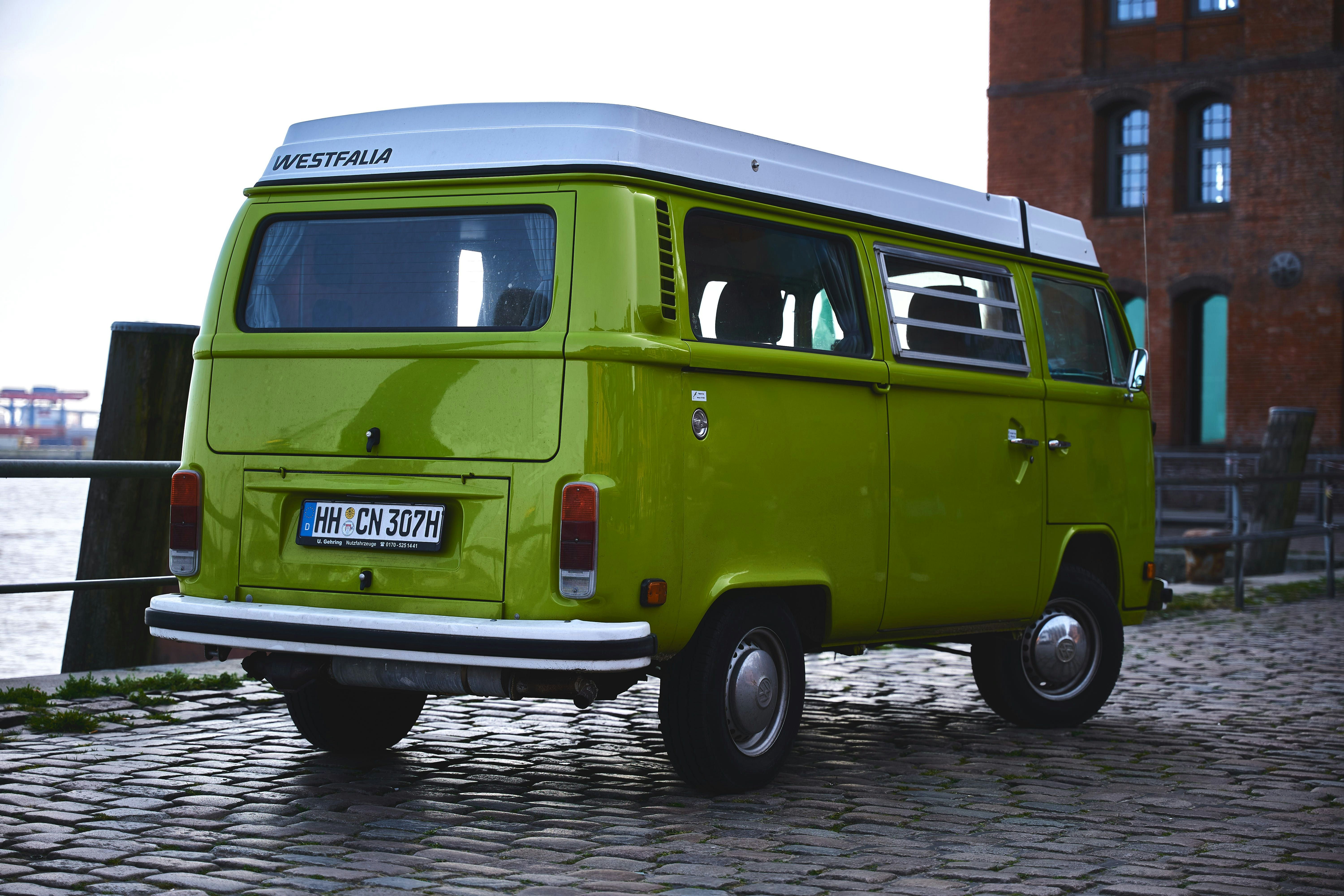 green and white volkswagen t-2 van parked on gray concrete pavement during daytime