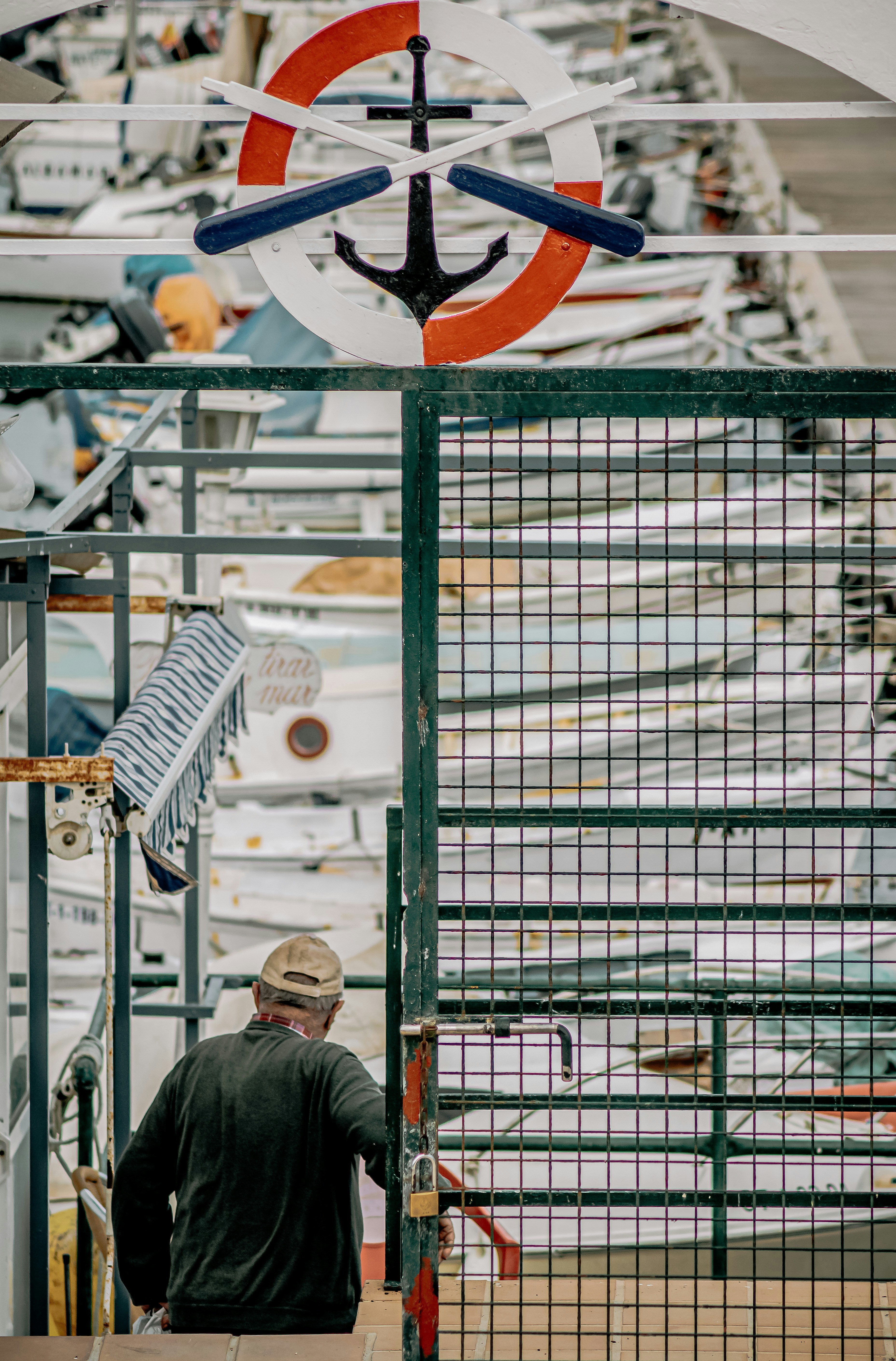 man in gray jacket standing beside gray metal fence during daytime