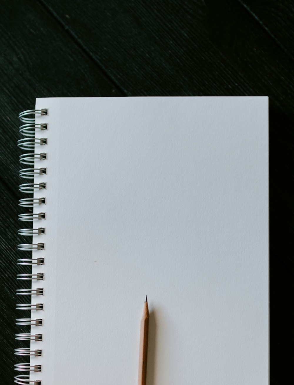 Cuaderno de espiral blanco sobre mesa de madera negra