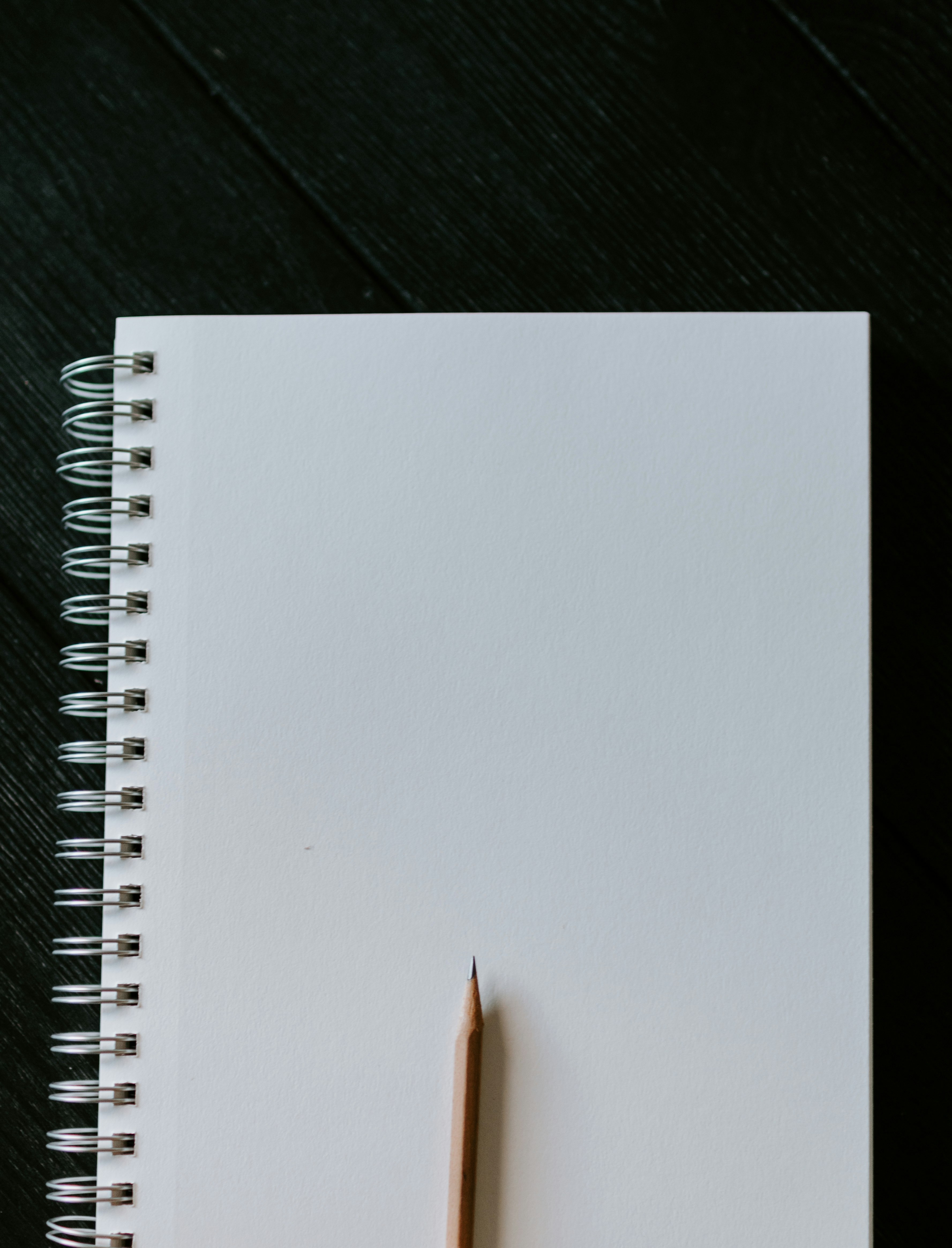 white spiral notebook on black wooden table