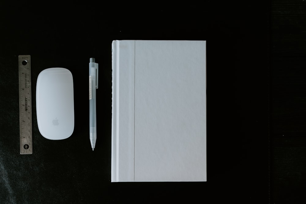 a mouse, a book, and a pen on a table