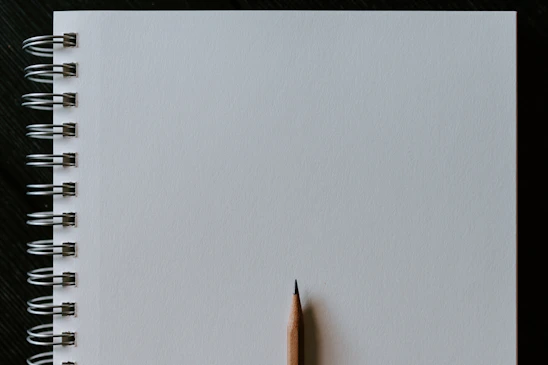A clean, empty notebook page with a soft pencil resting on the side, inviting creativity.