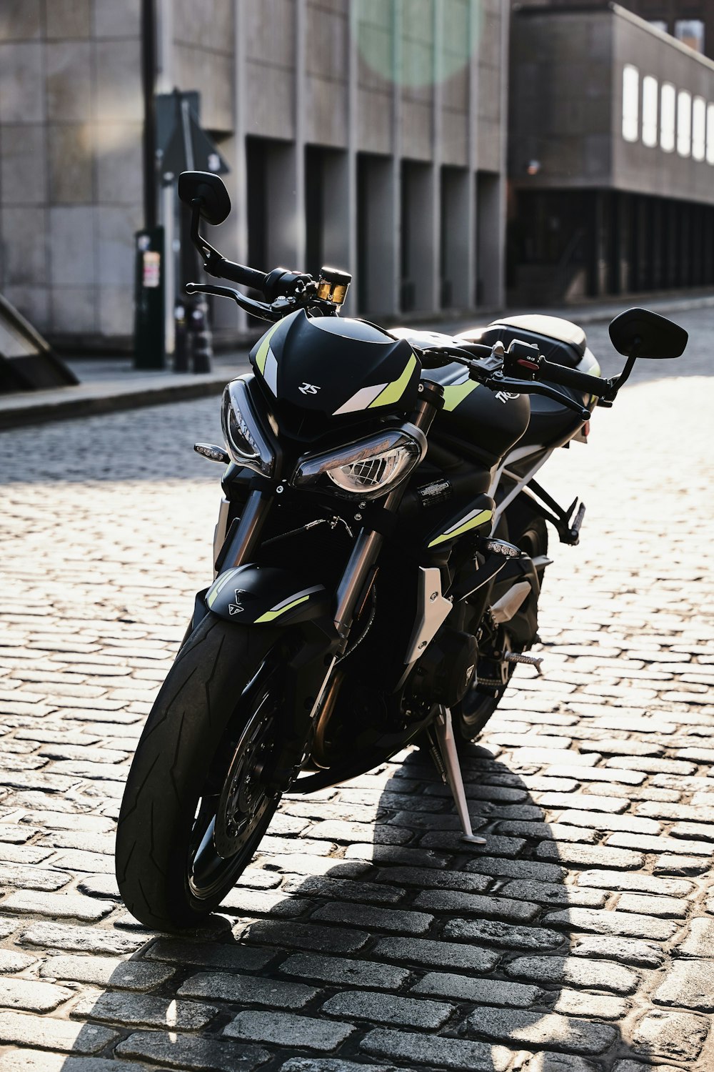 a black motorcycle parked on a cobblestone street