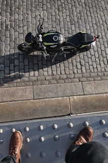 Pair of sturdy motorcycle boots standing on gravel beside a parked bike