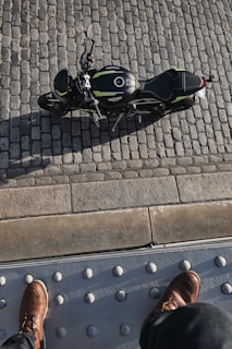 Pair of sturdy motorcycle boots standing on gravel beside a parked bike
